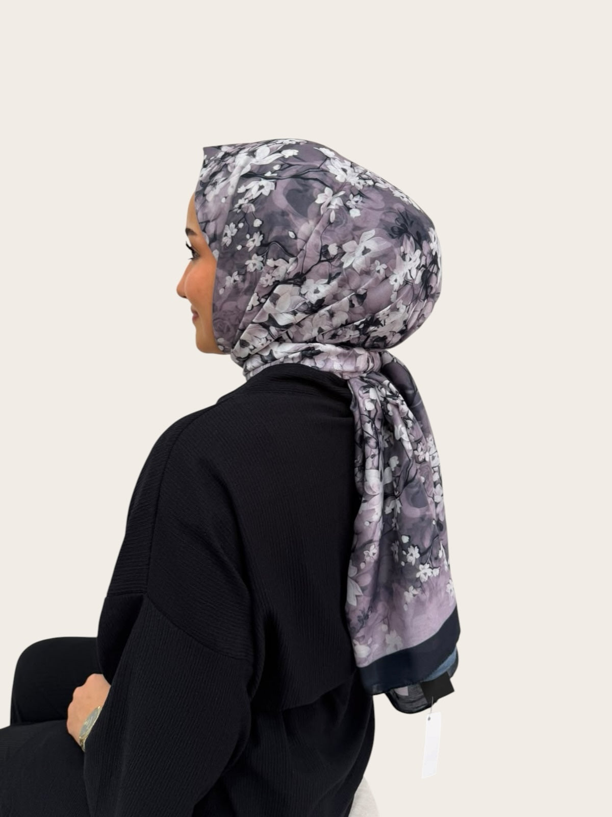 Loressina marka gri ve siyah tonlarında çiçek desenli, ipek dokulu şal takmış kadın profilden görünüm.